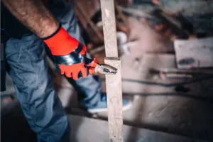 An HVAC technician working on an AC unit connection in an attic.