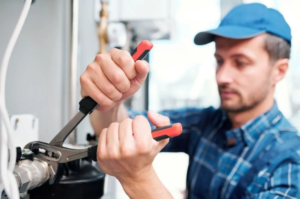 An HVAC technician tightens a valve on a new unit installation.