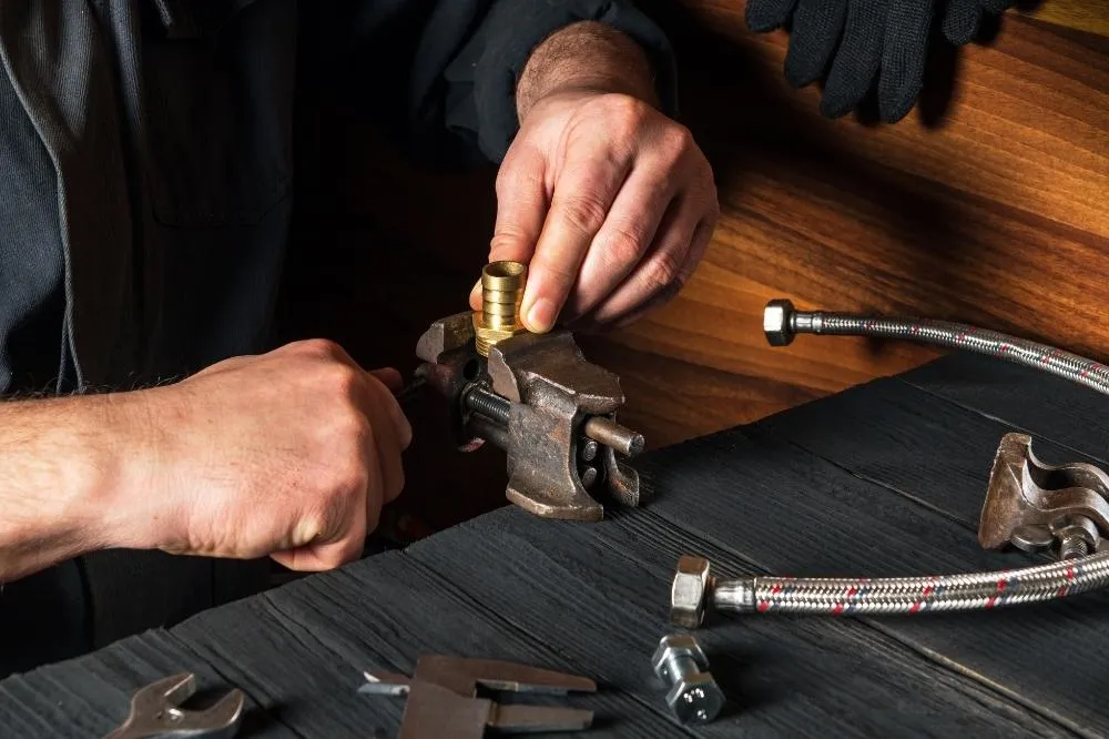An HVAC expert assembles new components with a vise.