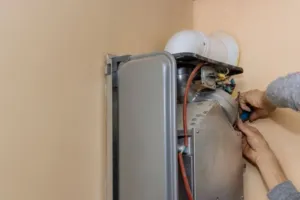 An HVAC expert tightens up a screw head on a new furnace installation. 