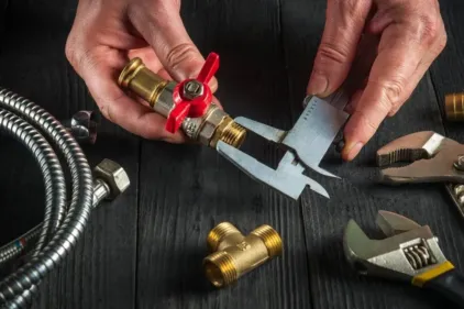 An HVAC professional assembling parts using a calipers.