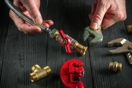 An HVAC repair expert tightening a valve with a wrench for a heater replacement.