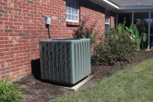 An AC unit newly installed stands against a building. 