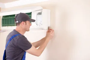 A photo of an AC expert working on the electrical portion of an AC unit.